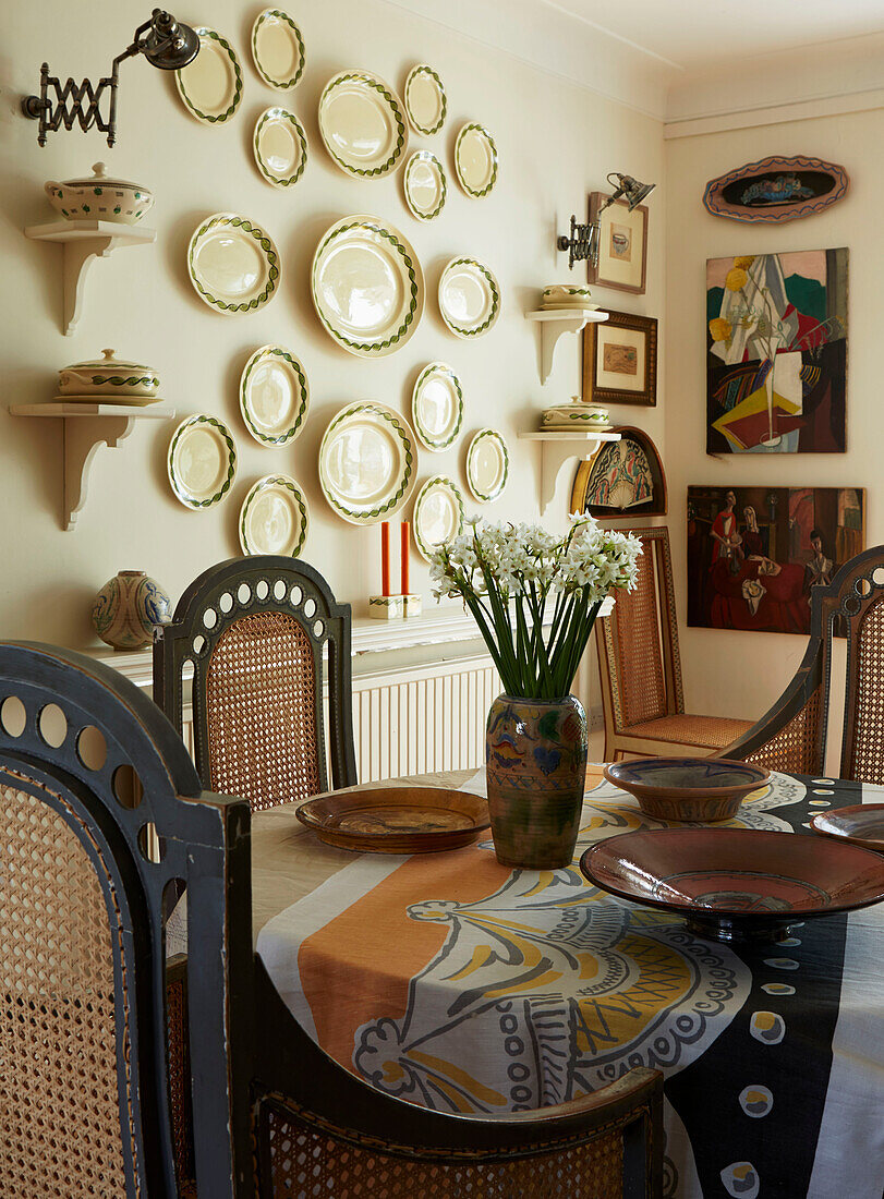 Cut flowers on dining table with decorative plates in London home, England, UK