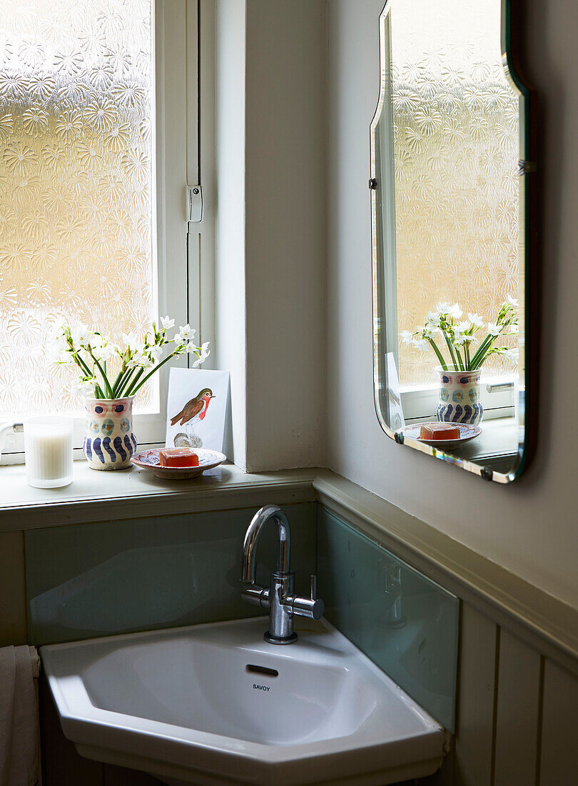 Verchromte Armatur am Waschbecken mit Spiegel unter dem Fenster im Badezimmer eines Hauses in London, England, UK