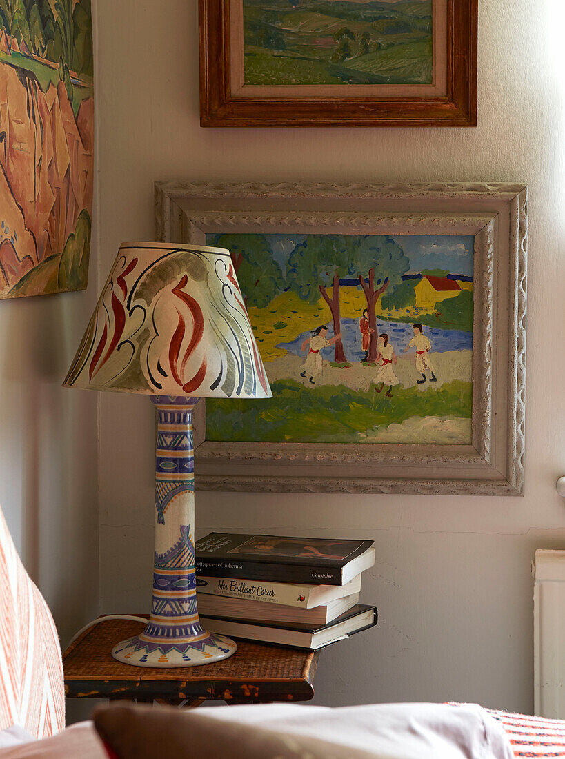 Lamp and books with artwork on bedside table in London home, England, UK
