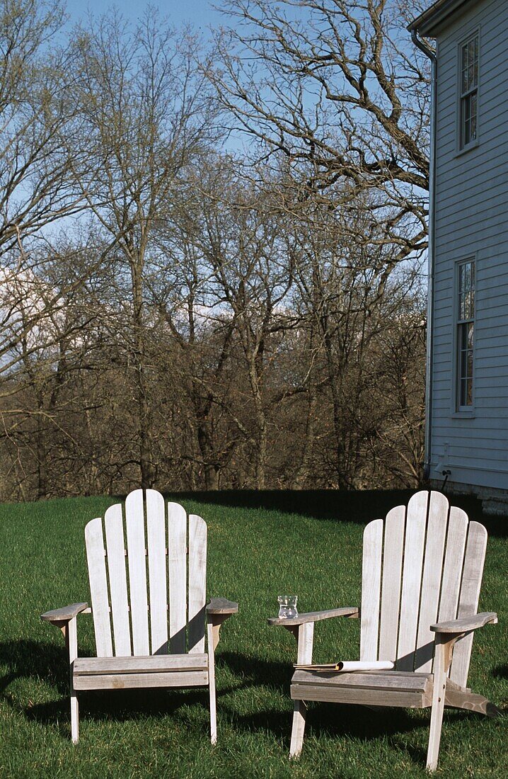 Stühle im Freien auf dem Rasen mit kahlen Bäumen im Hintergrund