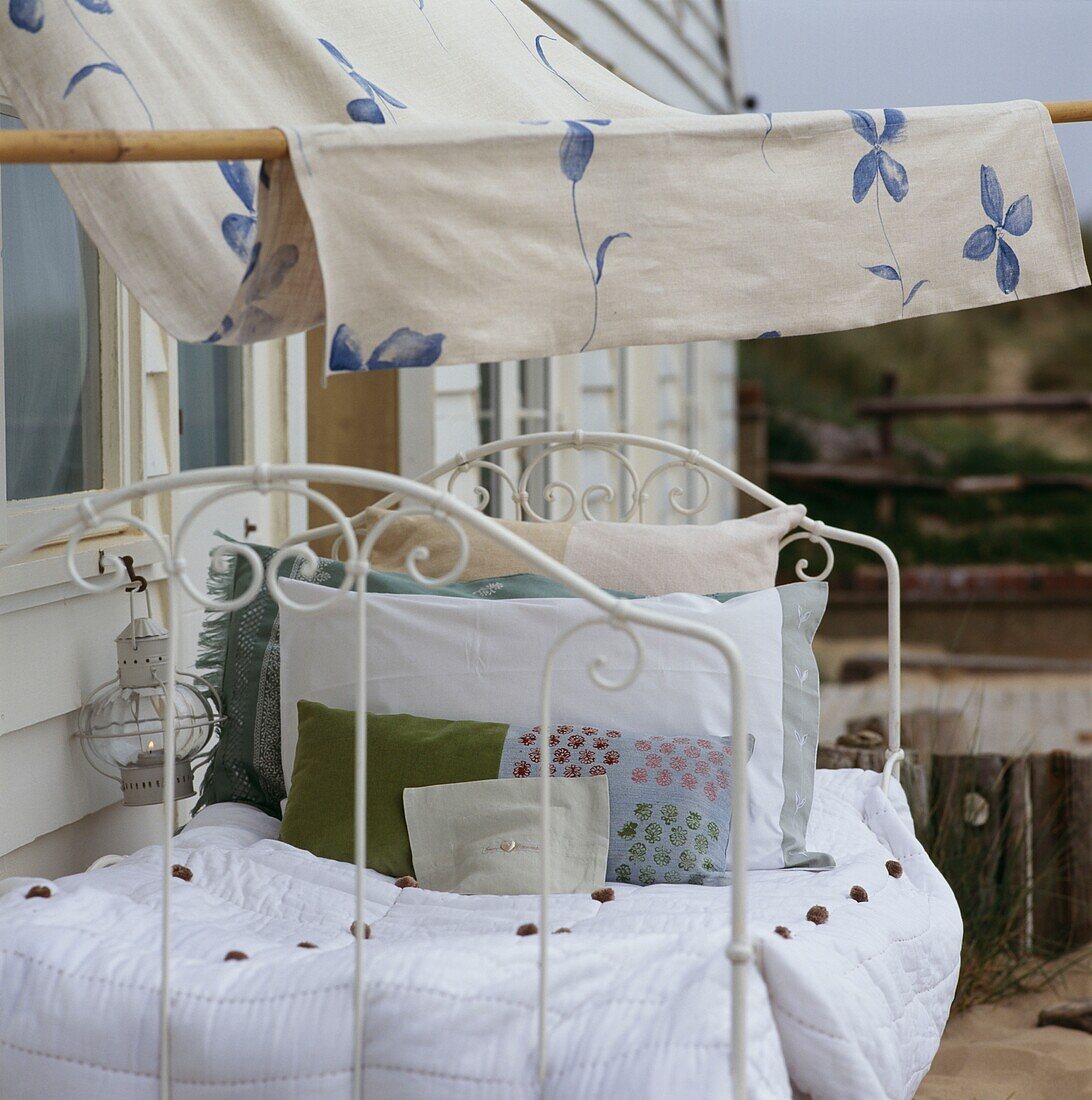 Iron bed and pillows with canopy outside beach house