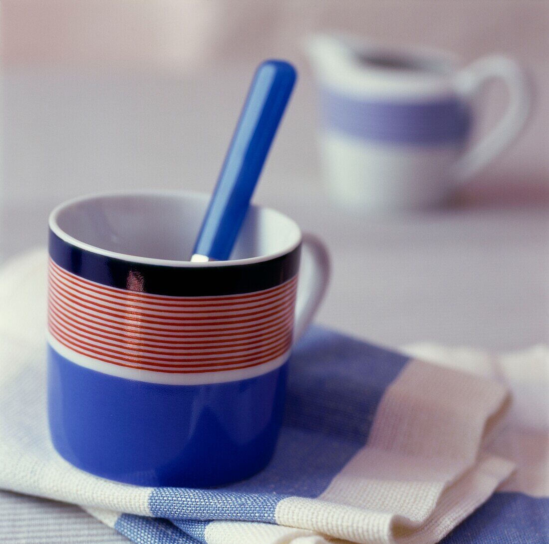 Blue handled spoon in striped blue and red cup