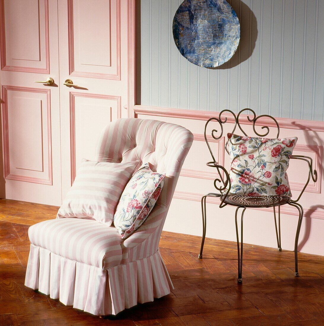 Pink striped and wrought iron chairs with cushions in panelled room 