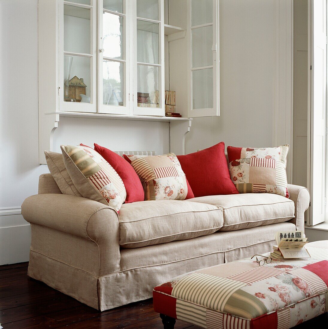 Cremeweißes Sofa mit Kissen und niedrigem Ottomanenhocker mit farblich abgestimmtem Stoff