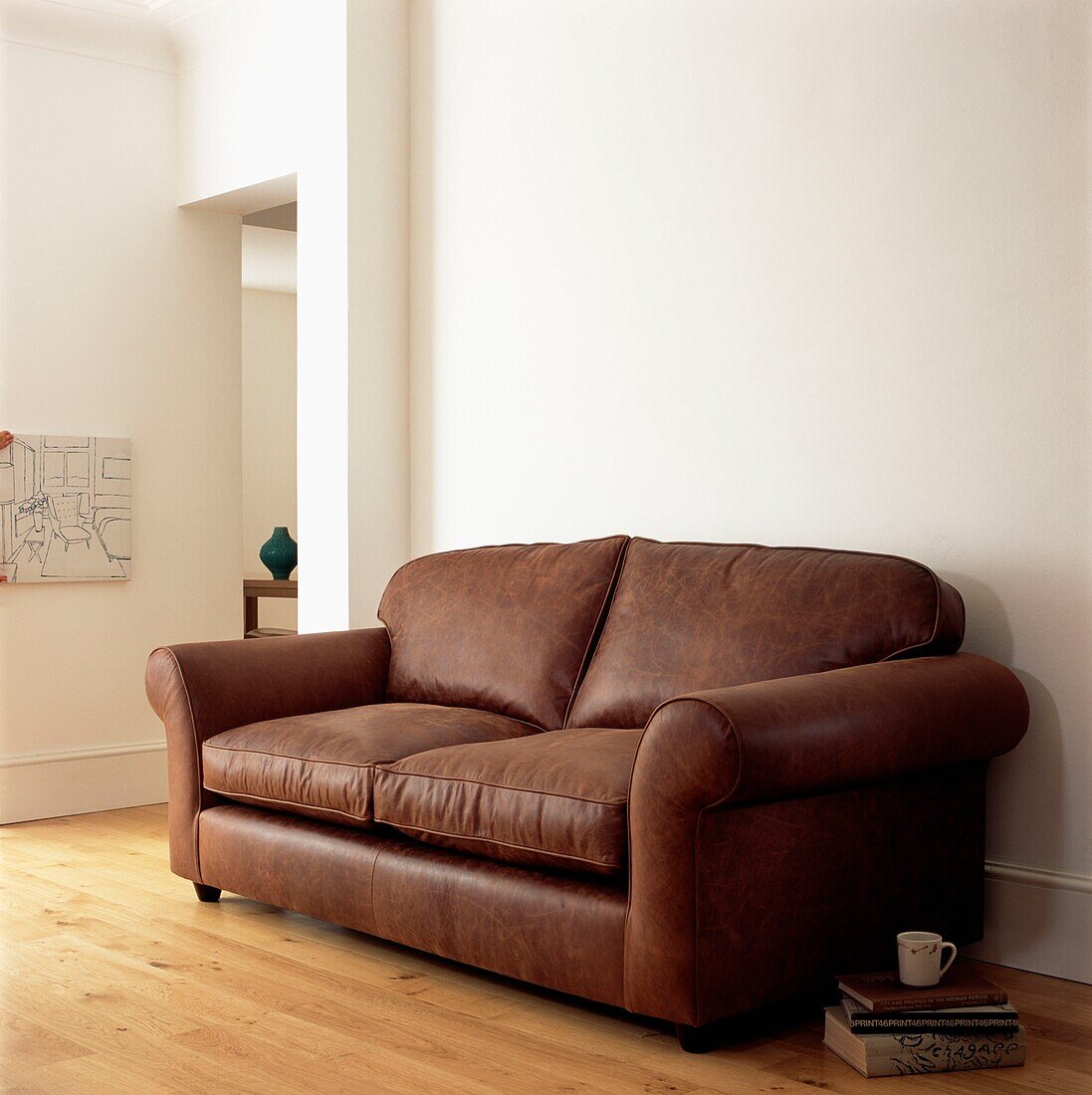 Brown leather sofa in white room with wooden floors