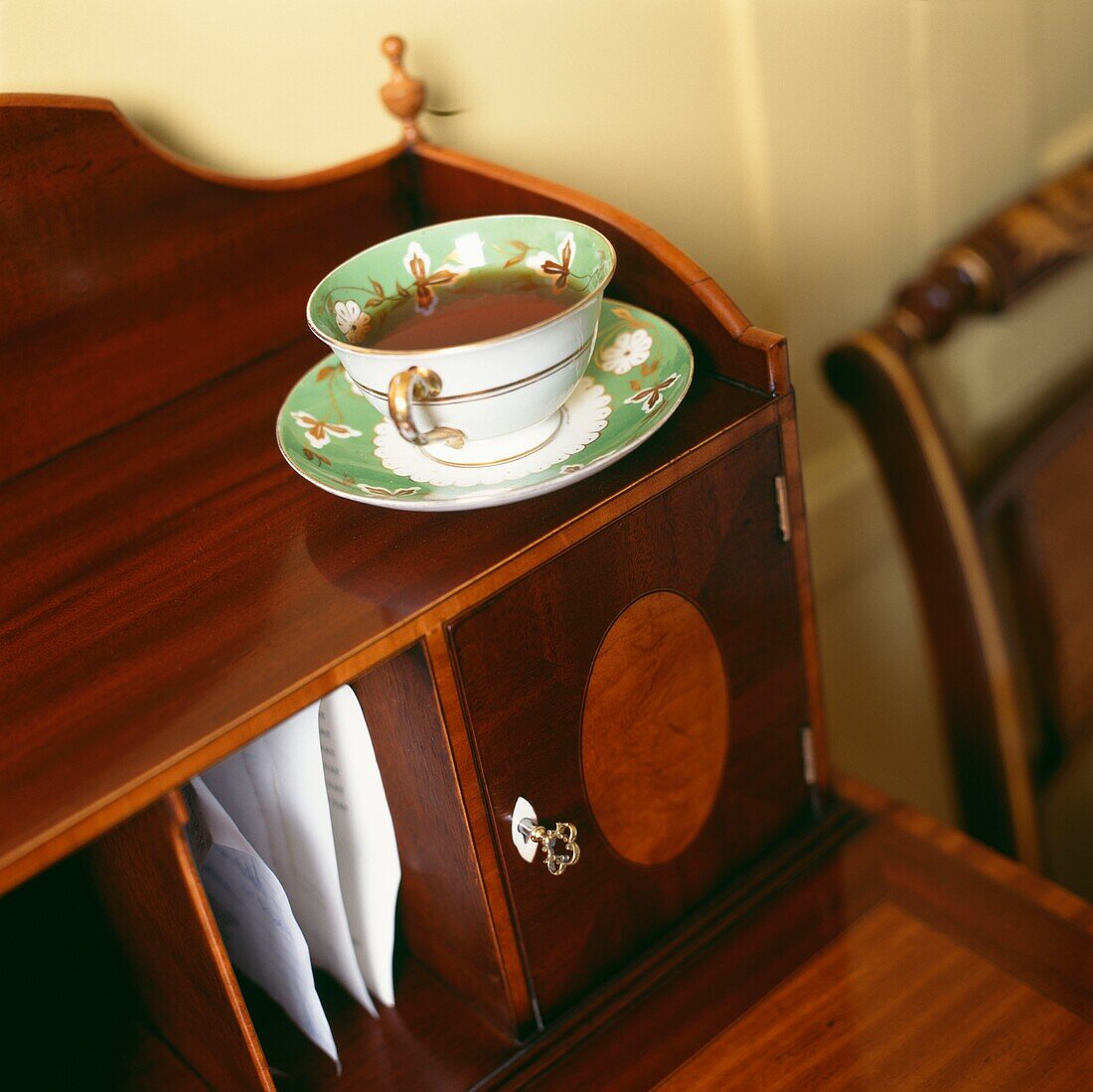 Teetasse und Untertasse auf einer polierten Schreibkommode aus Holz