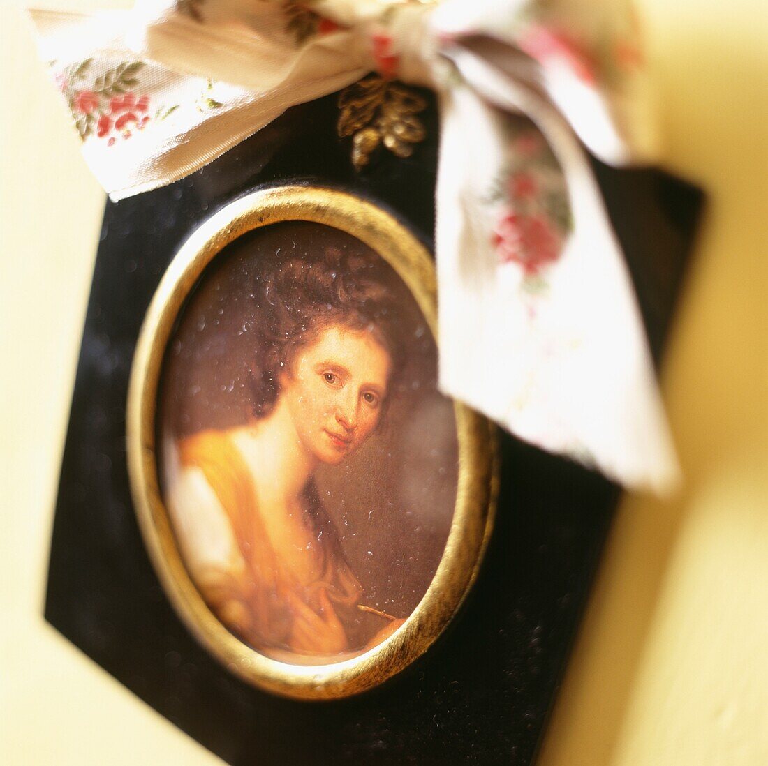 Portrait of woman in gilt picture frame tied with a fabric bow