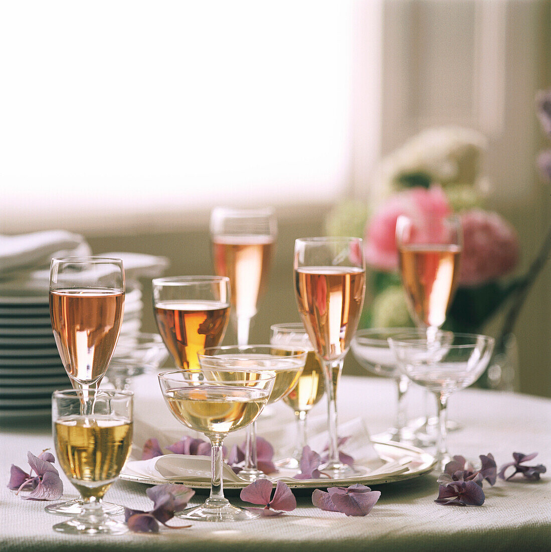 Tischplatte mit gefüllten Weingläsern, Tellern und Blumendekoration
