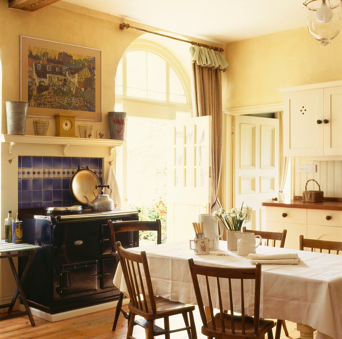 Stühle am Tisch in einer Landhausküche mit offener, sonnendurchfluteter Hintertür