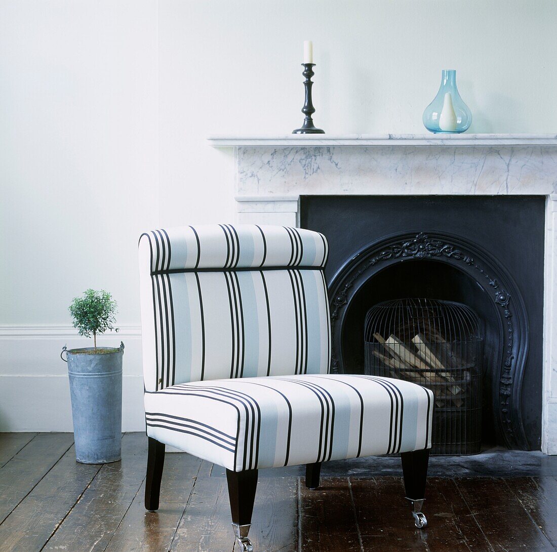 Striped armchair at fireplace with marble surround
