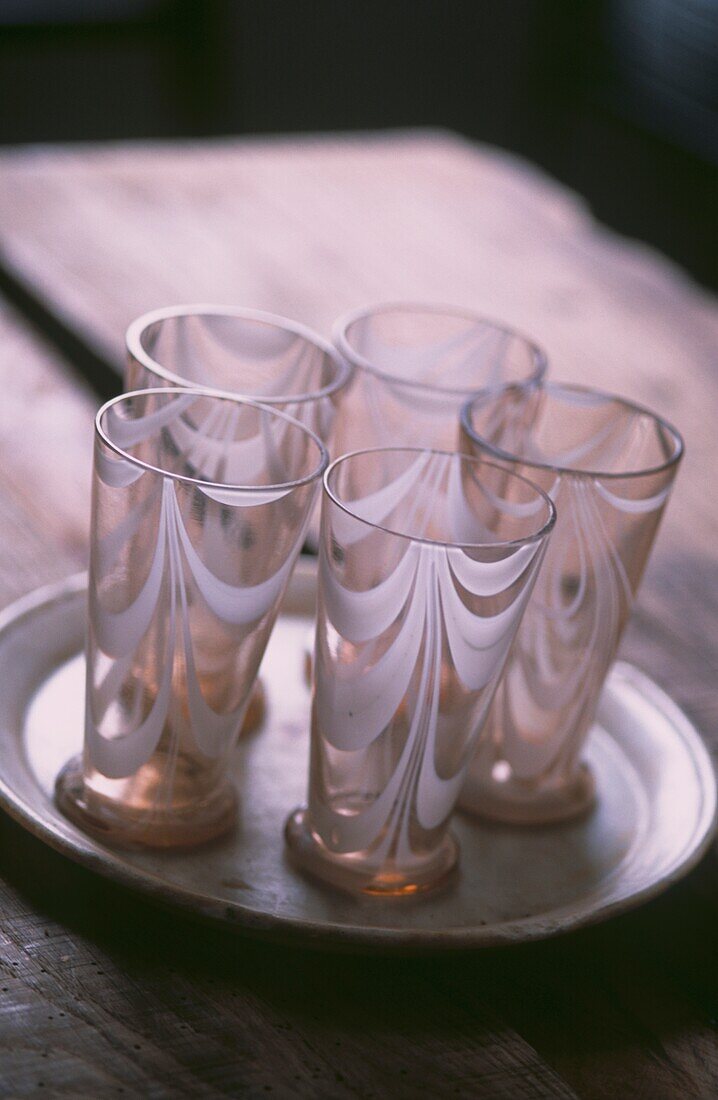 Satz von fünf kleinen farbigen Gläsern mit weißem Streifendesign auf Teller