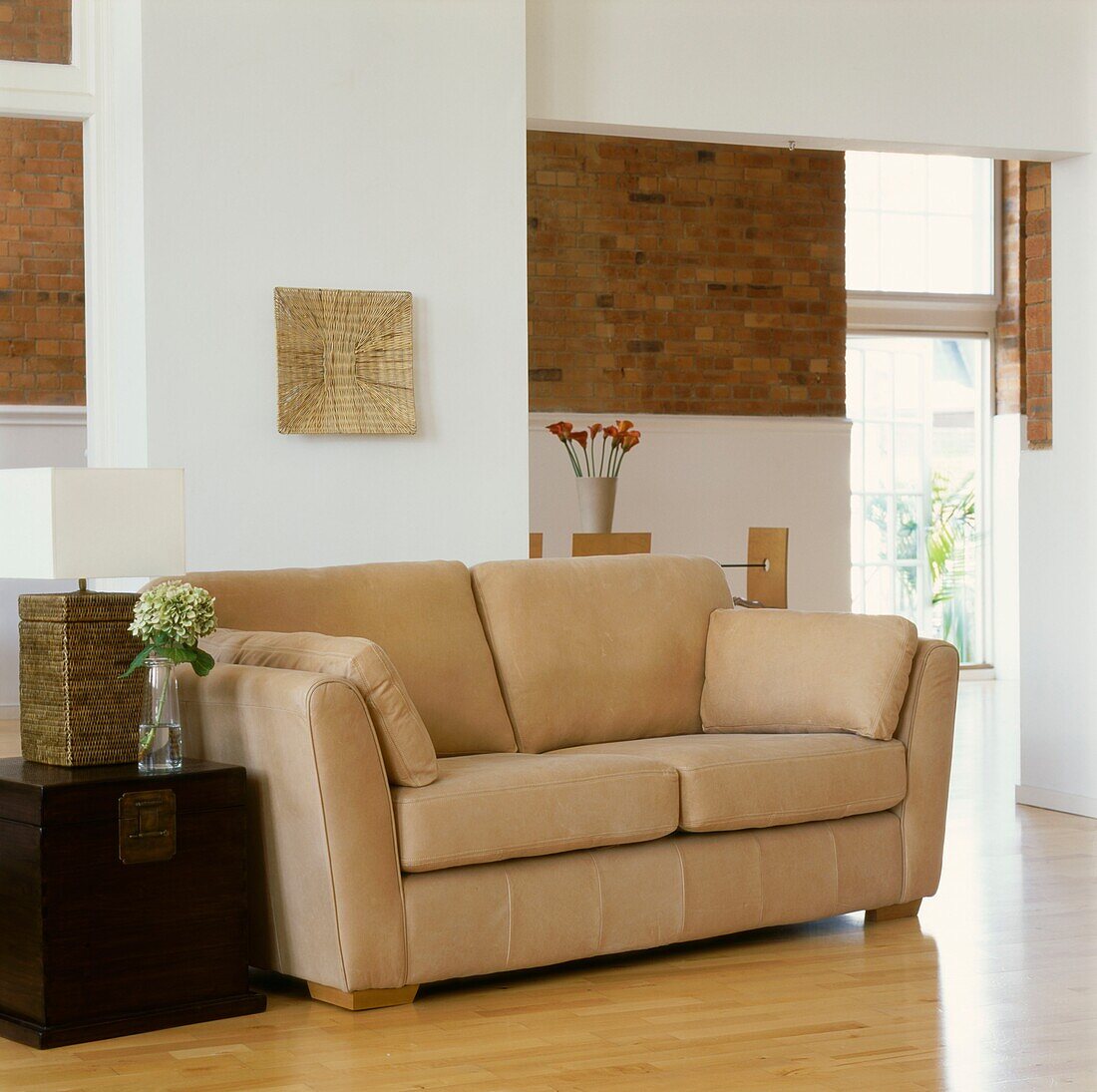 Beigefarbenes Sofa mit Truhe als Beistelltisch in einem Wohnzimmer mit freiliegender Backsteinwand