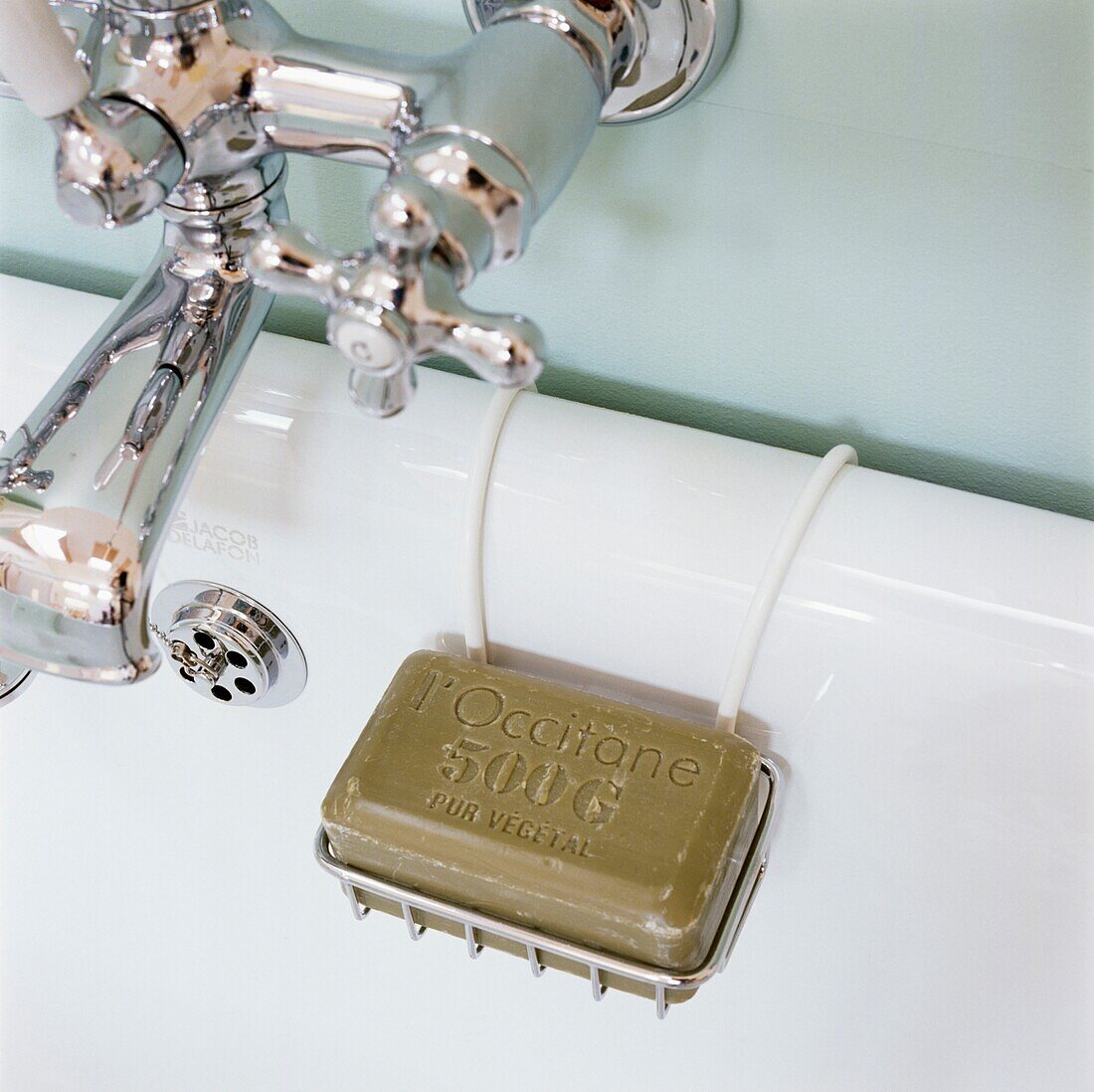 Seife in einem Regal neben silbernen Wasserhähnen im Badezimmer