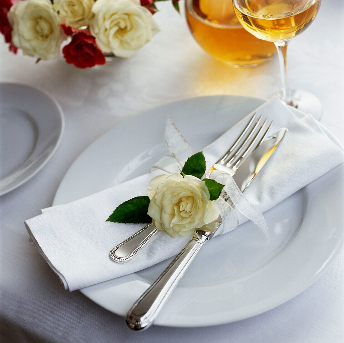 Einzelne Rose mit Besteck und Serviette auf einem Gedeck