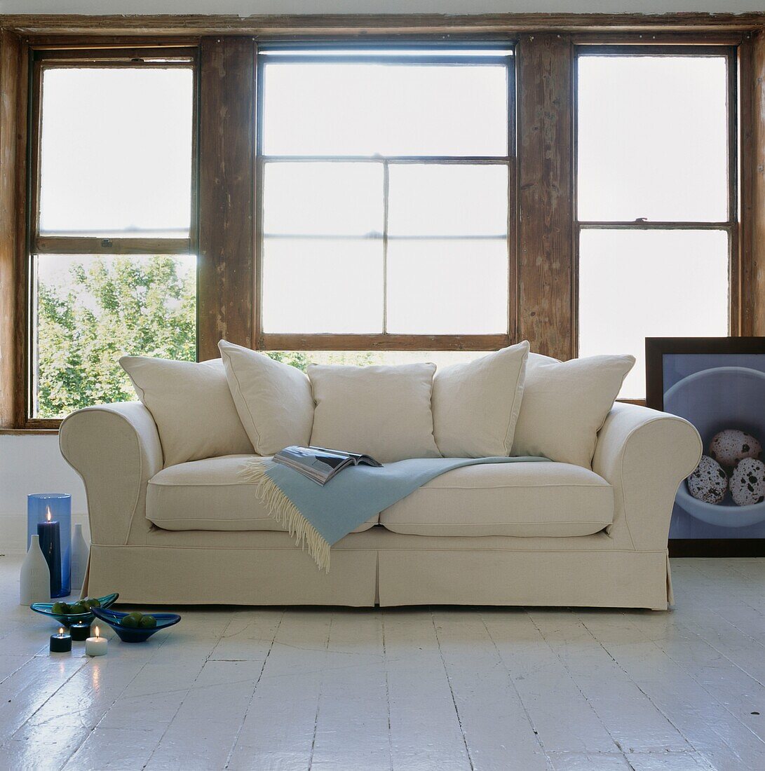 Pastel blues on cream sofa with unfinished sash window frames