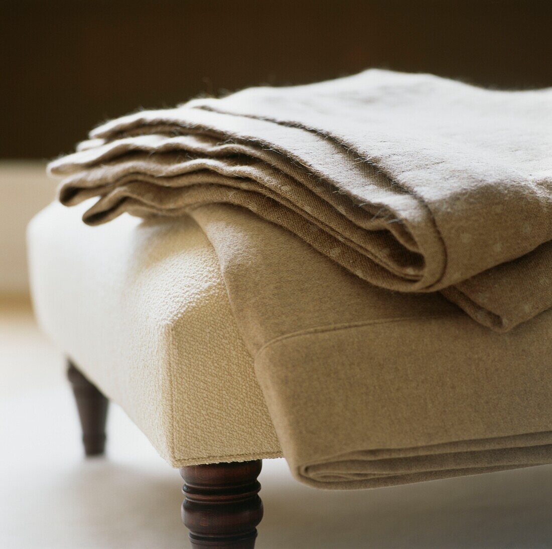 Neutral fabric folded on cream ottoman footstool