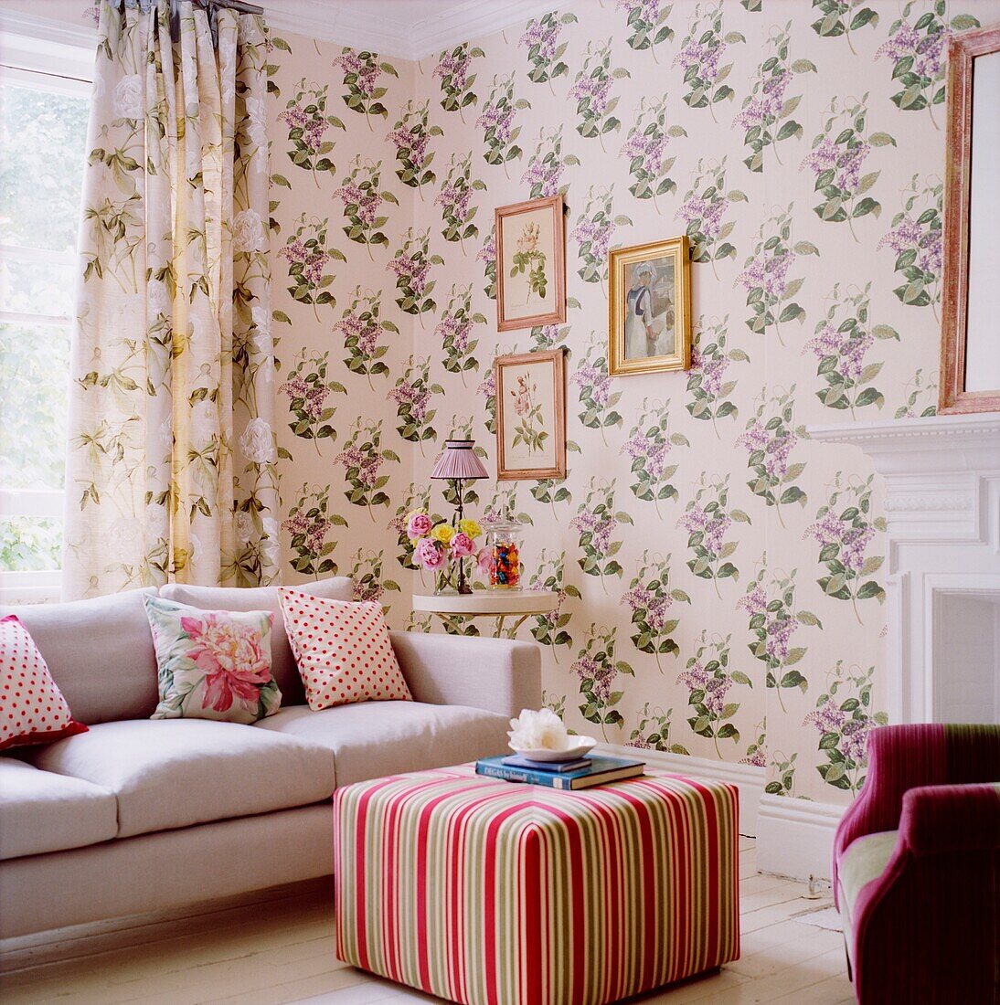 Striped ottoman in room with patterned floral print wallpaper and contrasting curtains