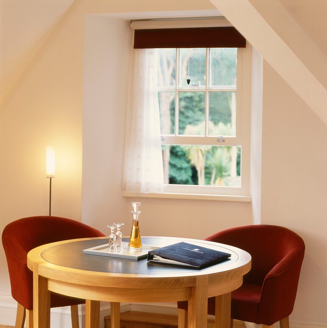 Red armchairs at table in front of open sash attic window 