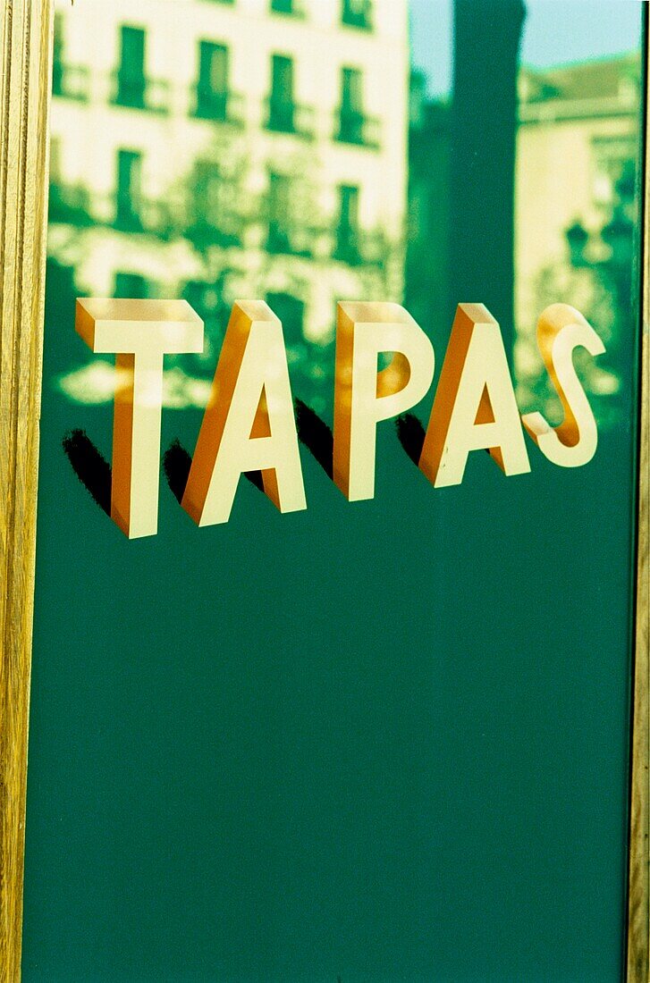 Gebäude spiegelt sich auf einem Tapas-Schild an der Tür einer Tapas-Bar in Madrid