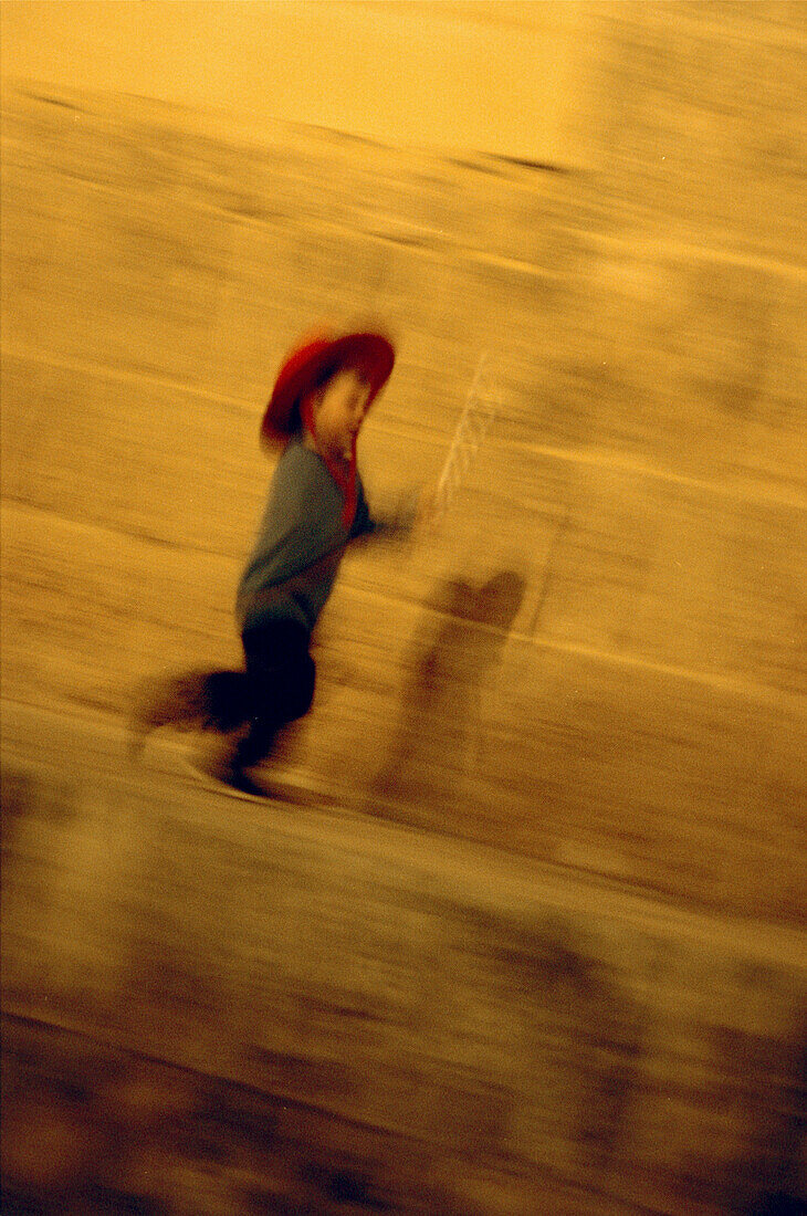 Young boy running along wall