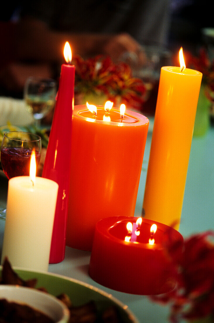 Tisch dekoriert mit brennenden roten und orangenen Kerzen