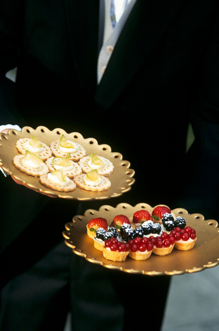 waiter serving dessert canapes and fruit tartlets