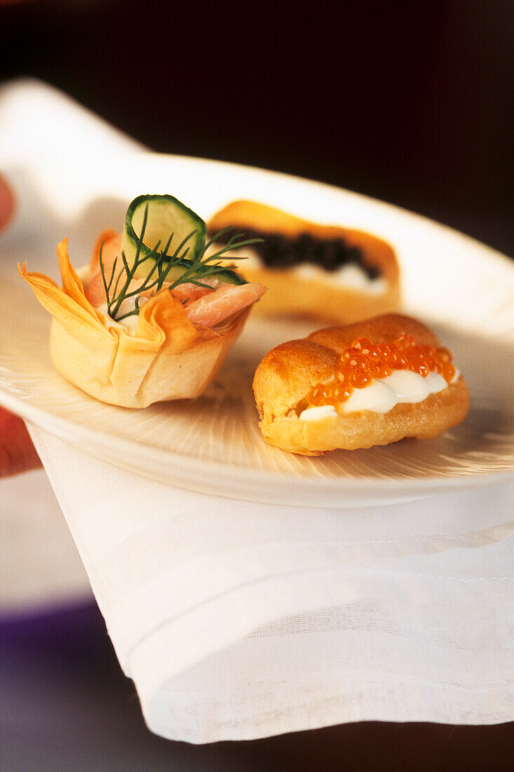 Caviar eclairs with smoked trout and cucumber filo tartlets