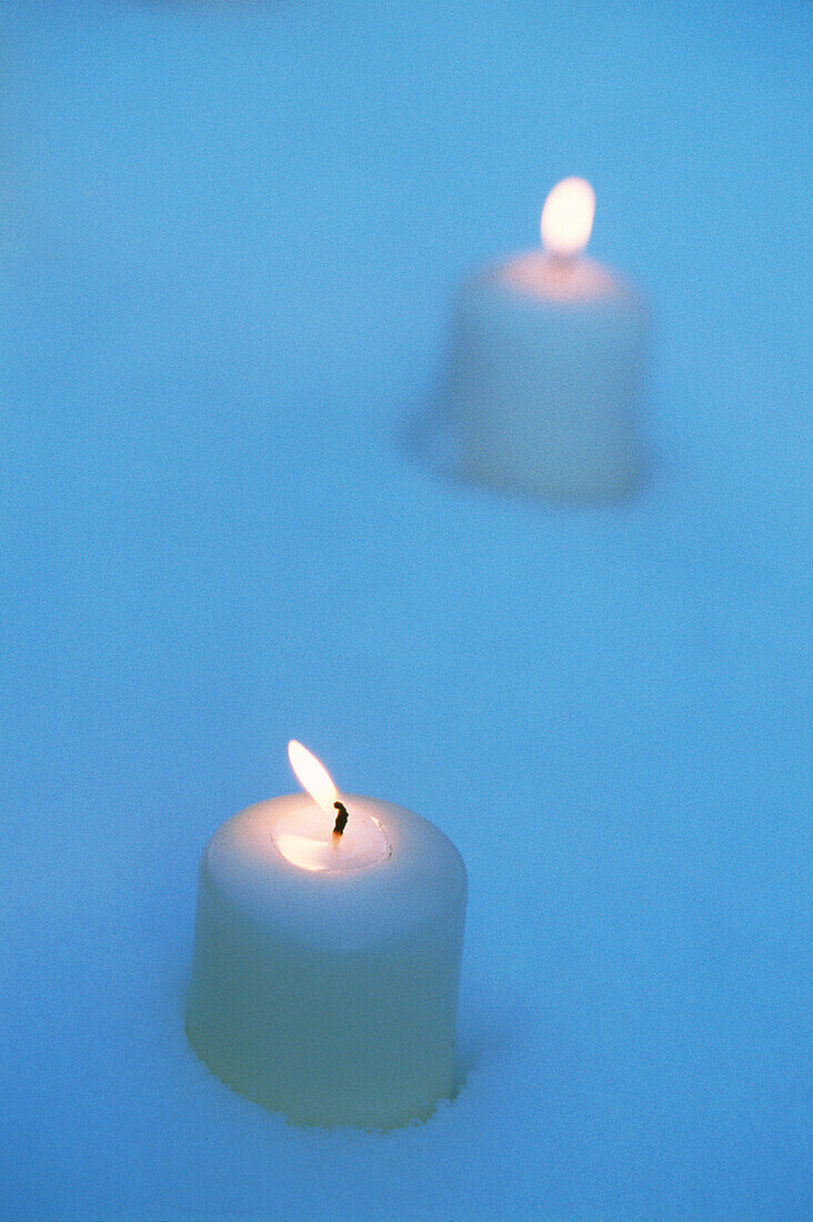 Two lighted candles in the snow