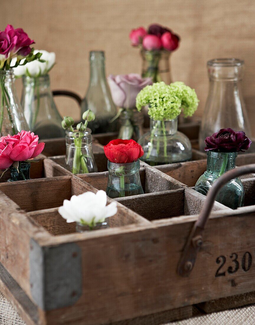Einstielige Blumen in Vasen in einer alten Holzkiste