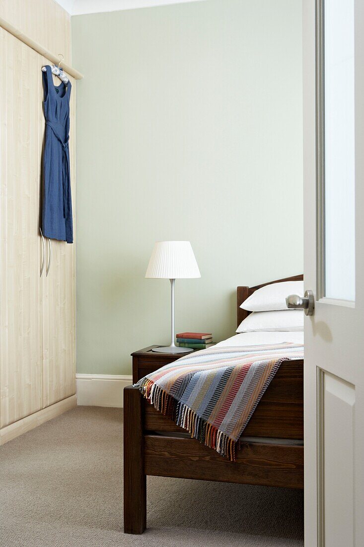 Kleid hängt am Kleiderschrank im pastellgrünen Schlafzimmer