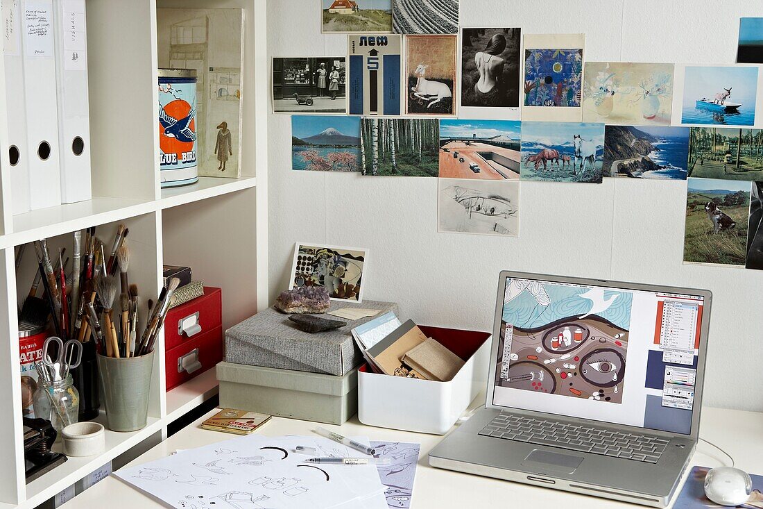 Postcards and art equipment with laptop on desk