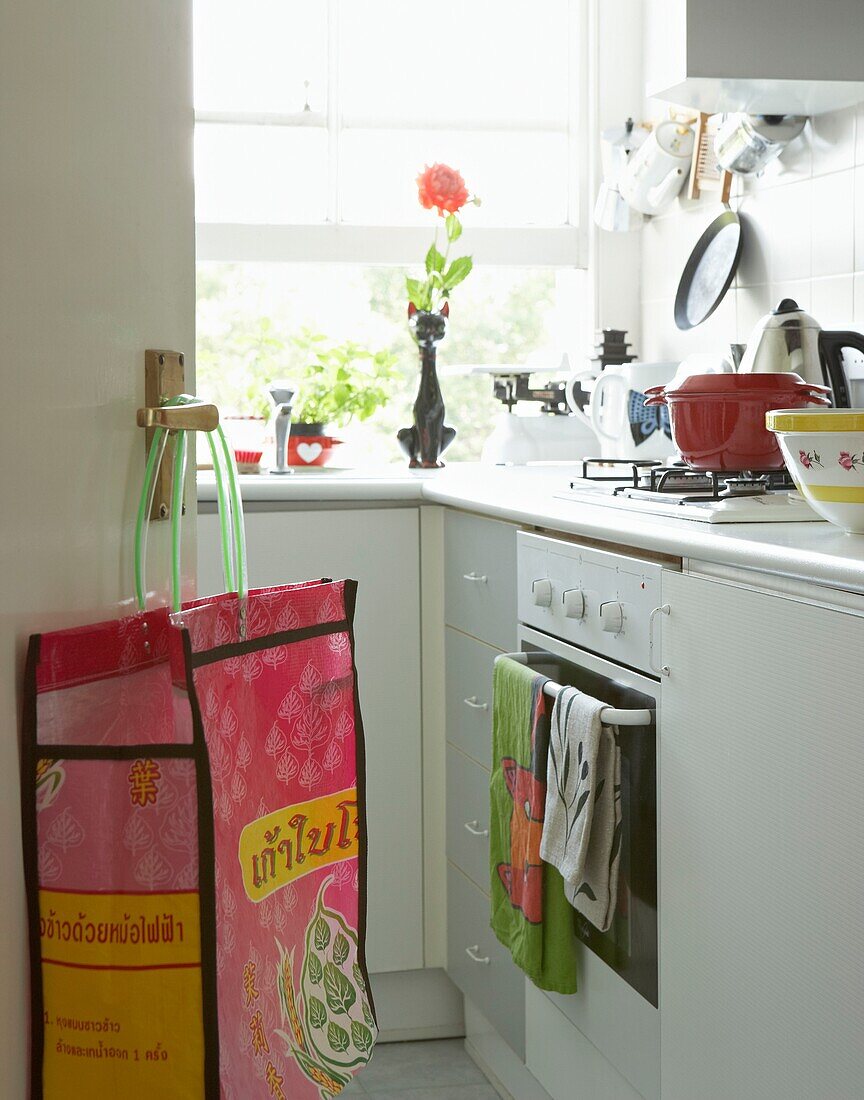 Shopping bag hangs on kitchen door with teatowels on oven