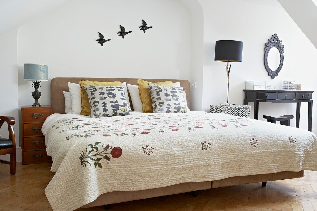 Fliegende Enten über dem Bett mit Steppdecke und Kissen mit Schmetterlingsmotiv in einem Londoner Haus UK