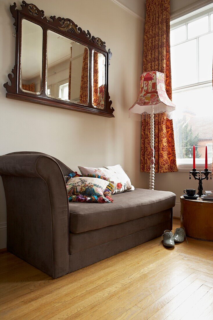Braune Chaiselongue unter antikem Spiegel am Fenster eines Londoner Hauses in England UK