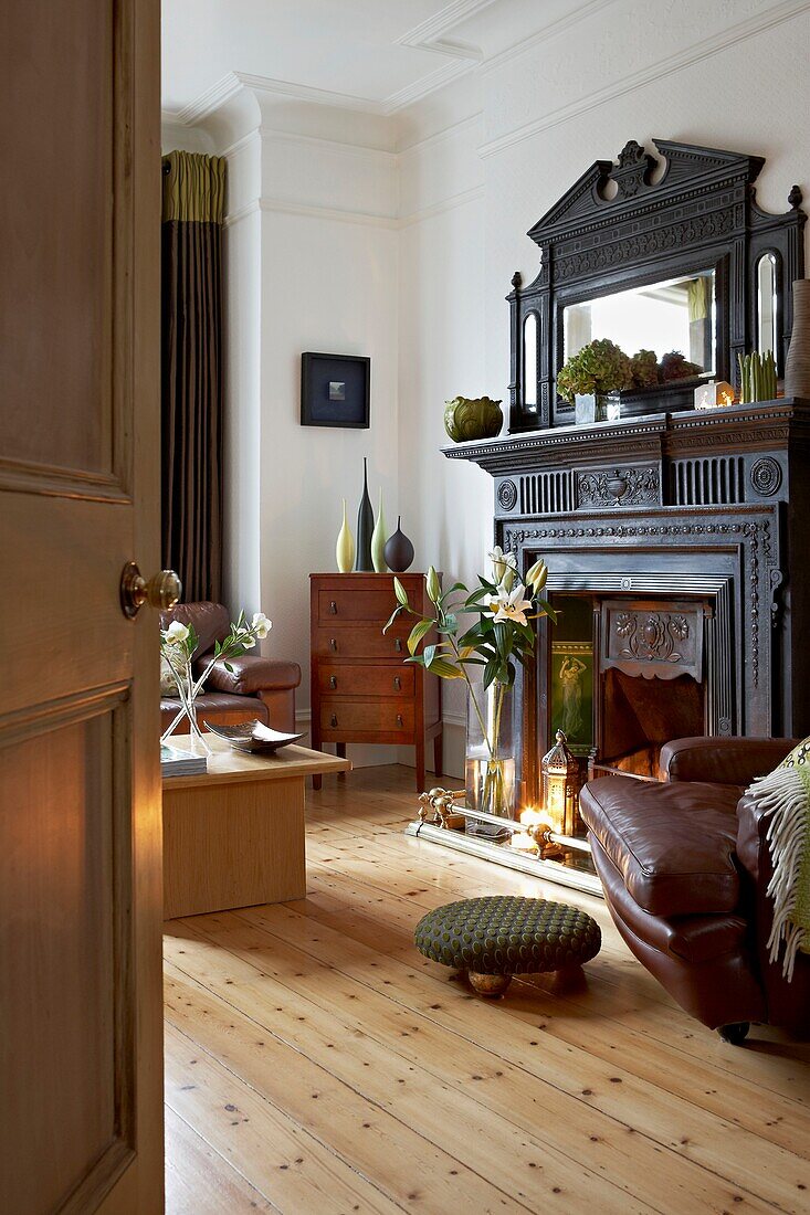 Brown leather armchair with foot rest with antique fireplace in London home   UK