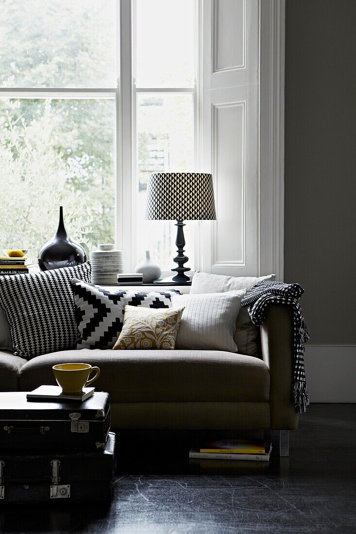 Schwarz-weiß gemusterter Lampenschirm und Kissenstoff auf dem Sofa vor dem Wohnungsfenster