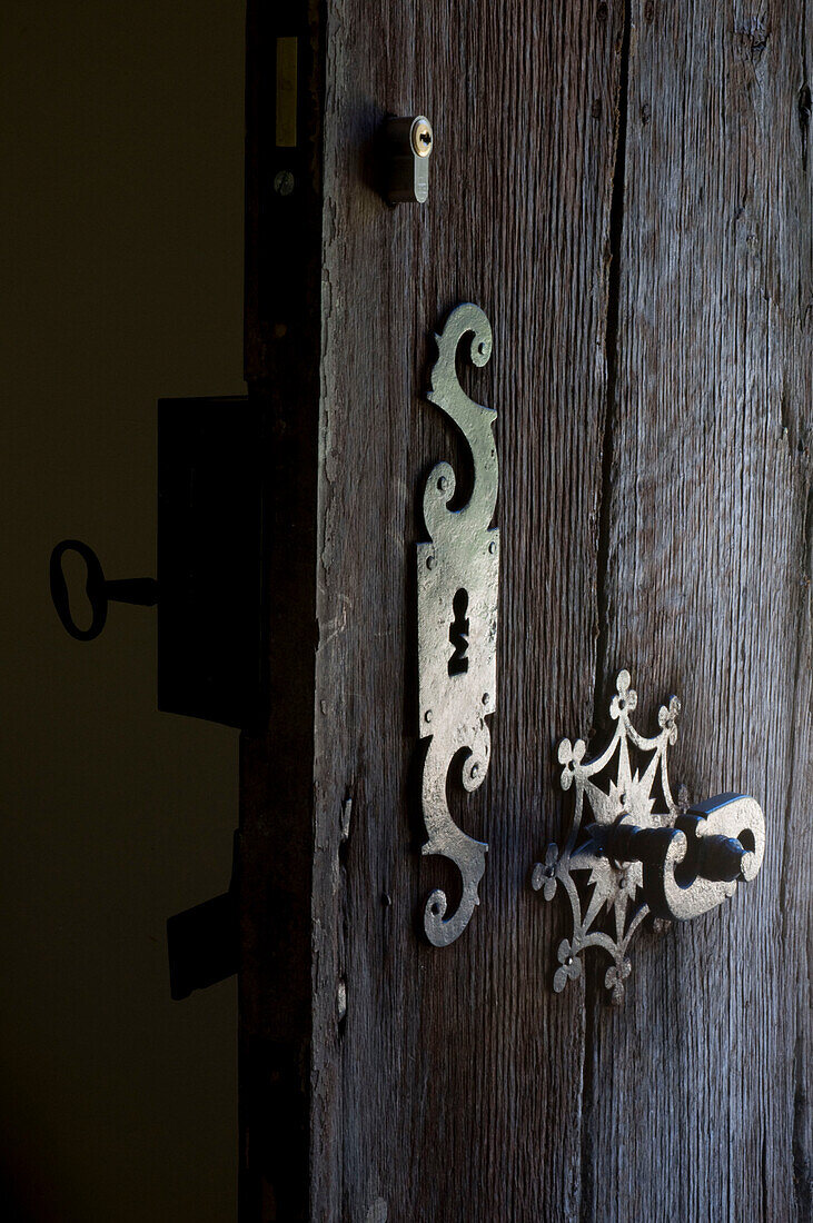Detail einer Holztür mit verschnörkelten Eisenbeschlägen