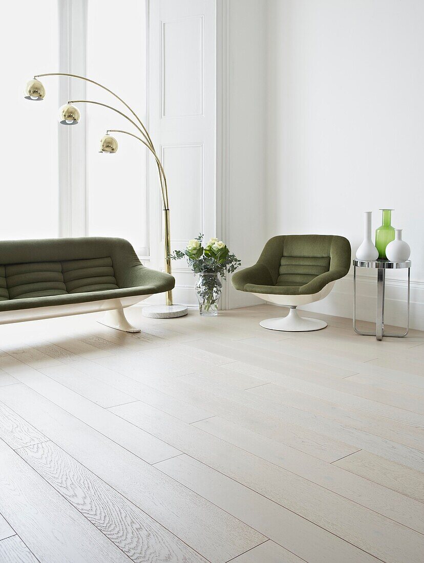 Grüner Sessel und Sofa im Retrostil im Wohnzimmer mit weiß gestrichenen Dielenböden