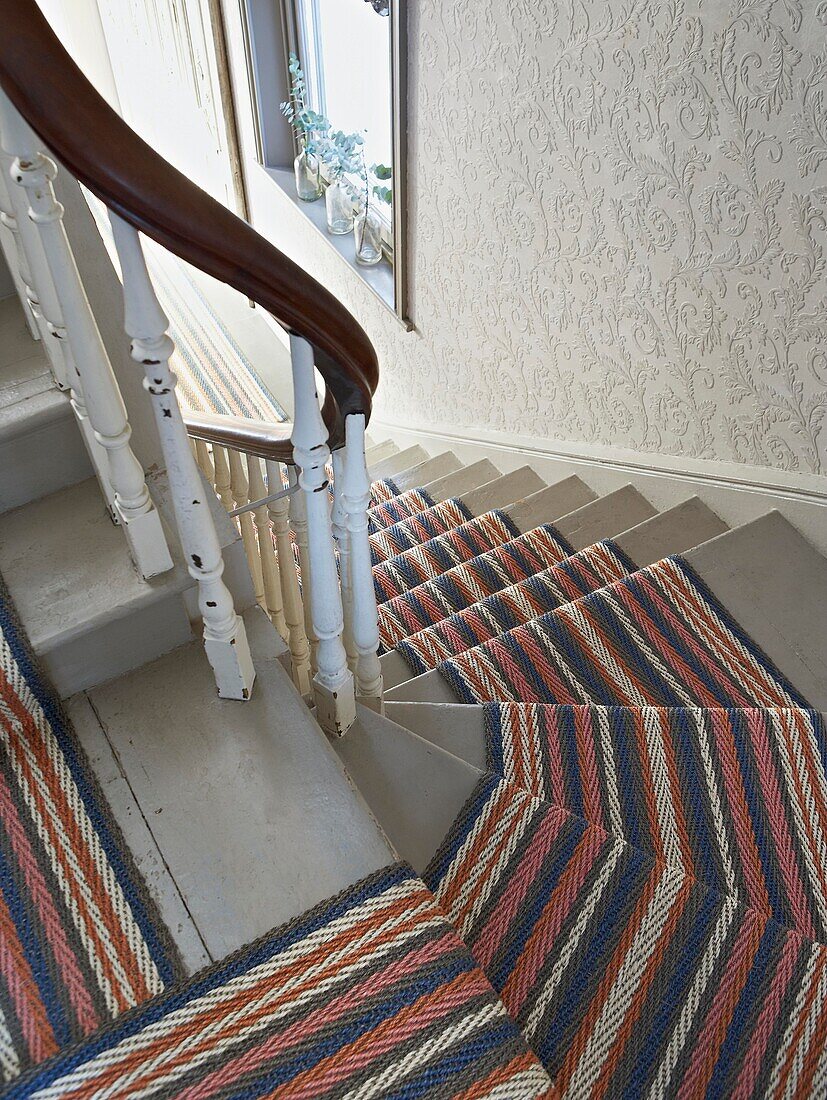 Striped carpet on staircase with wooden handrail