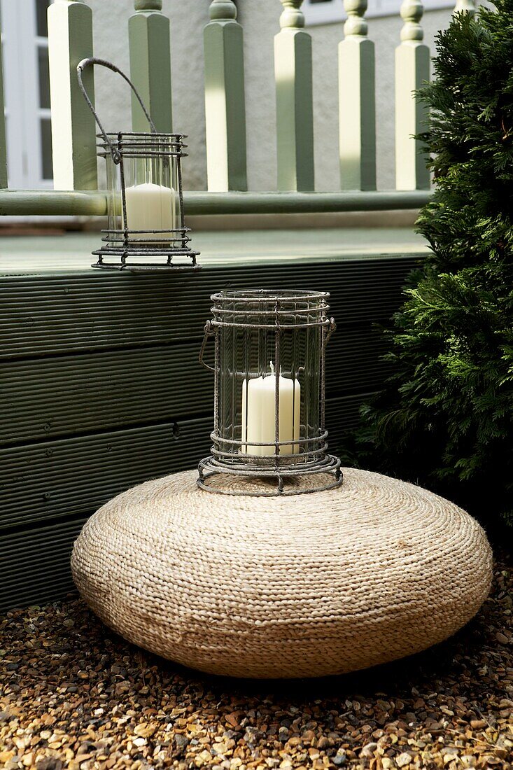 Rattan poof and lanterns beside a decked area of the garden