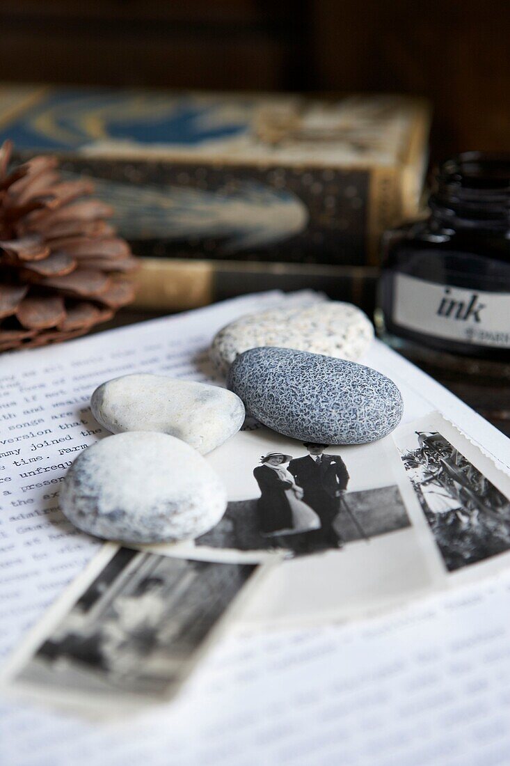 Schreibtisch mit Kieselsteinen, einem Brief und einigen schwarz-weißen Familienfotos