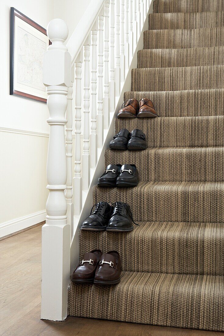 Männerschuhe auf einer mit Teppich ausgelegten Treppe London England