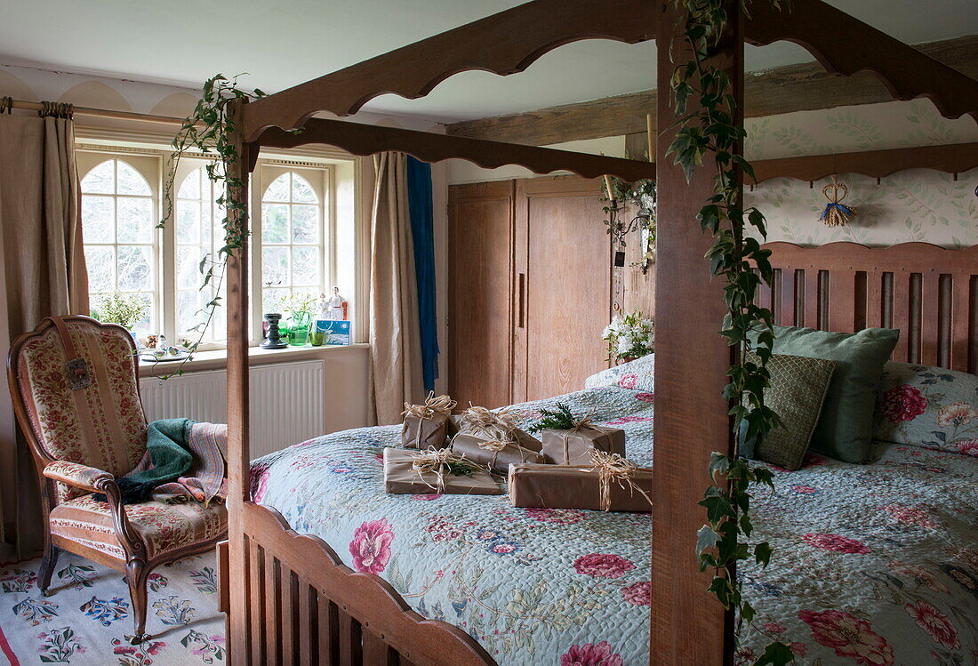 Himmelbett aus Holz mit Weihnachtsgeschenk, eingewickelt in braunes Papier, Benenden cottage, Kent, England, UK