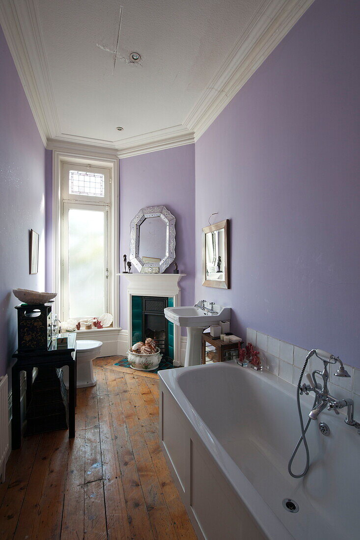 Weiße Badewanne und Waschbecken im fliederfarbenen Badezimmer des Hauses in Greenwich, London, England, UK