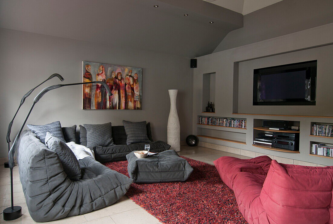 Red and grey seating with plasma screen in living room of contemporary Haywards Heath home,  West Sussex,  England,  UK