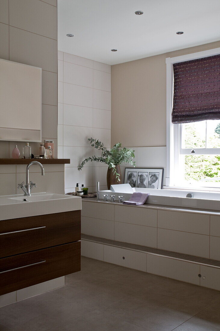 cSplit level bathtub with purple Roman blinds in decorative place Haywards Heath home,  West Sussex,  England,  UK