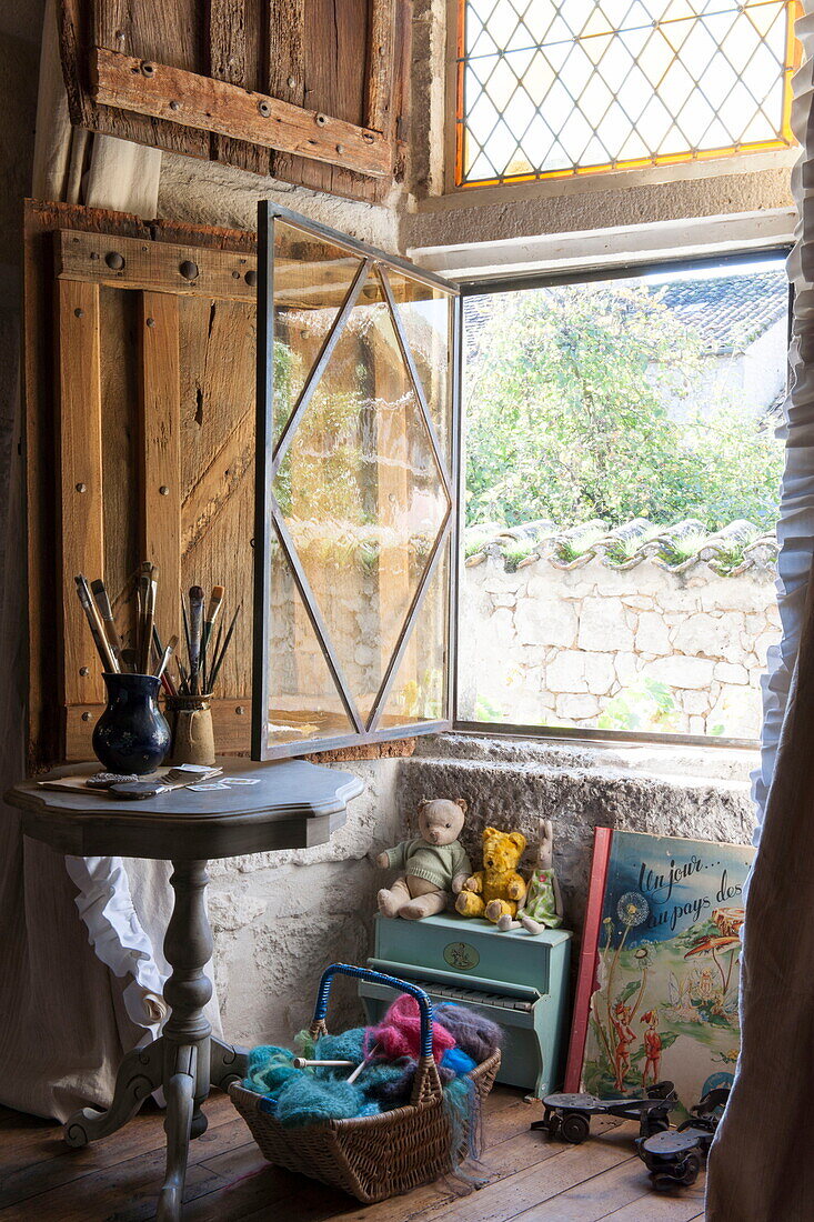Paintbrushes on side table at open window of Dordogne farmhouse interior,  France