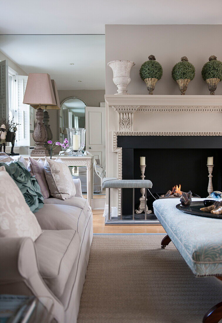 Sofa and Ottoman footstool in front of lit fire in Battersea home,  London,  England,  UK