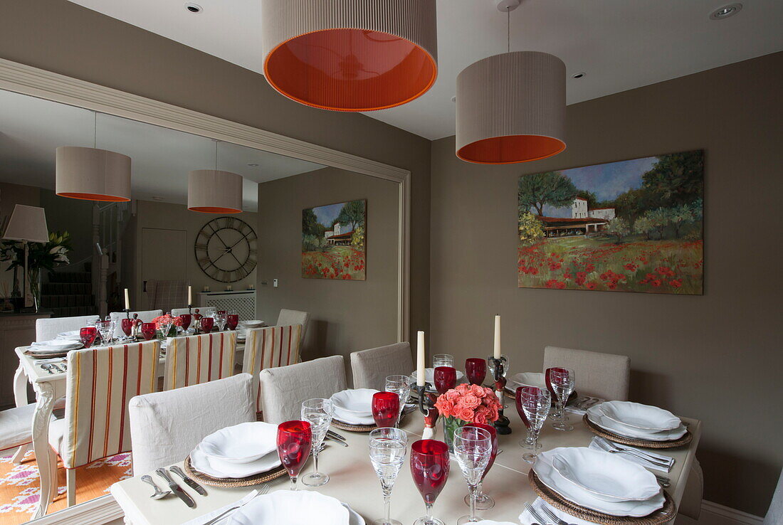 Table for eight with red wineglasses reflected in large mirror of Battersea home,  London,  England,  UK