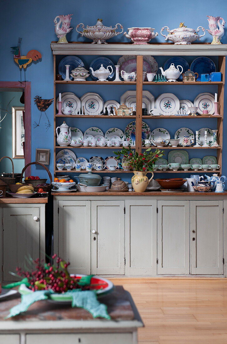 Verschiedenes Geschirr auf Wandregalen in der blauen Küche des Tiverton-Bauernhauses in Devon UK